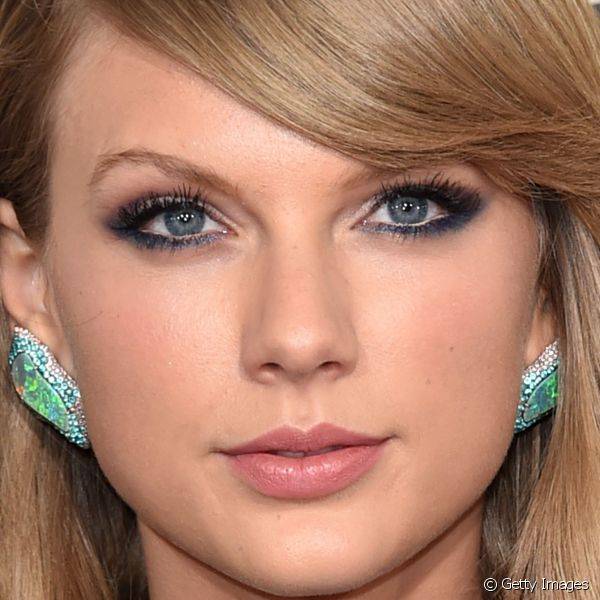 Taylor Swift usou um esfumado de sombra roxa nas p?lpebras superiores e completou o olhar esfumando azul rente aos c?lios inferiores: o truque ajuda a deixar o branco dos olhos mais vivo